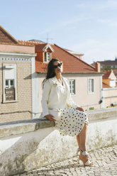 a lady wears a white blazer with white suit vest and polka dot printed skirt